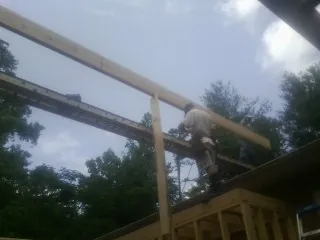 Carpenter setting a ridge beam over a new addition frame — Ice Dam Removal by Roofing Brothers in Menno