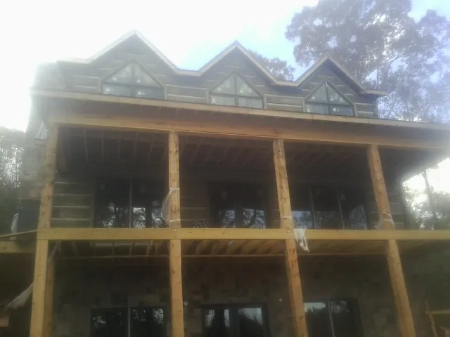 Dormers and porch framing on a large log home under construction — Roof Coating work by our crew in Menno
