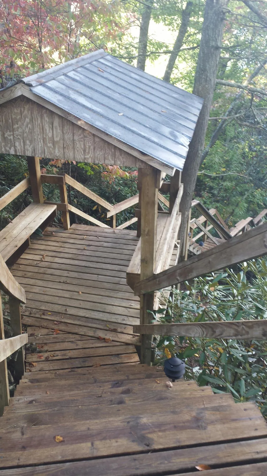Metal roofed shelter over wooden steps on a wooded walkway — Skylight Repair & Installation work by our crew in Menno