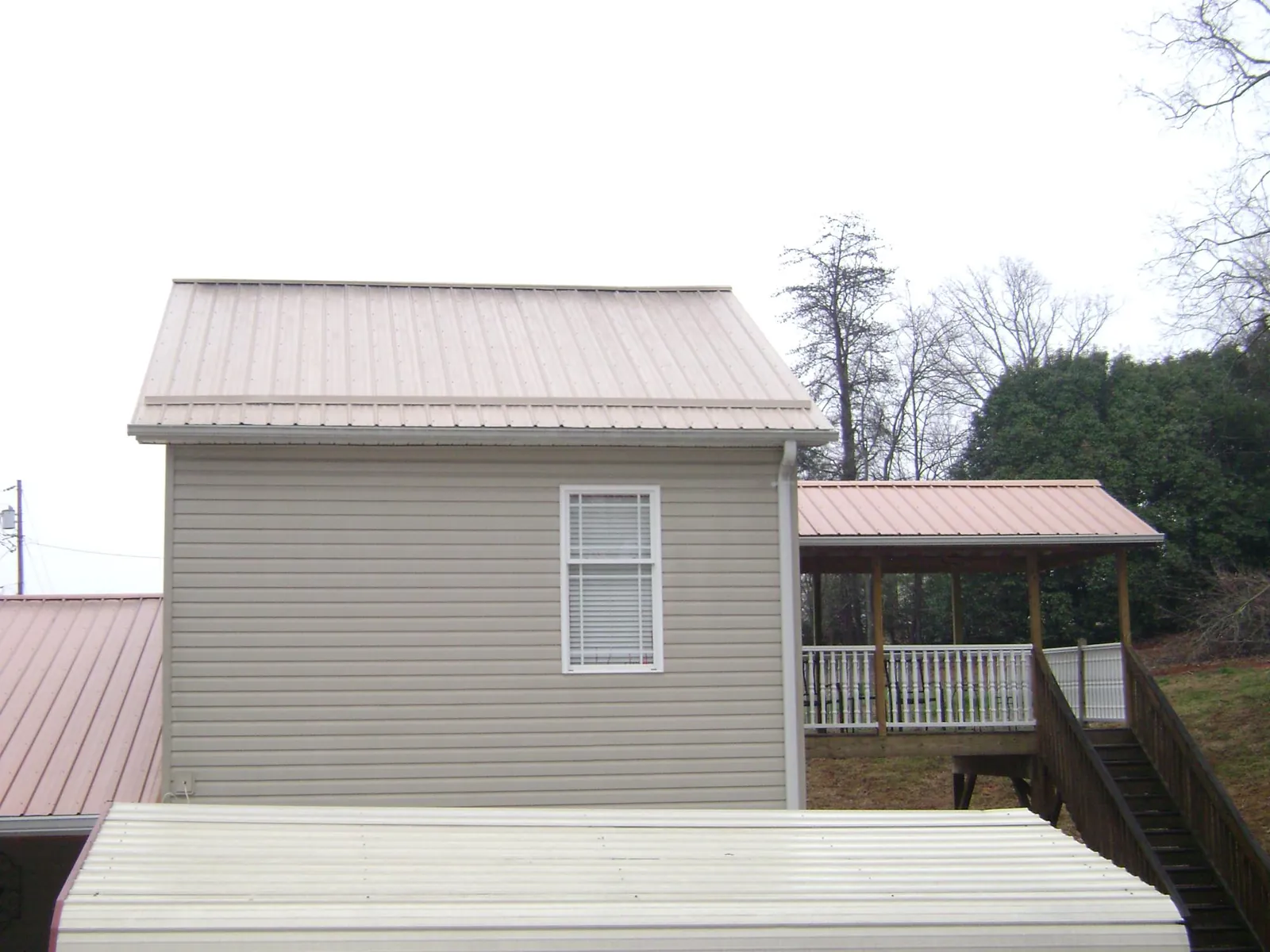Tan metal roofs on a two story addition and attached porch, from a Roof Replacement job in Menno
